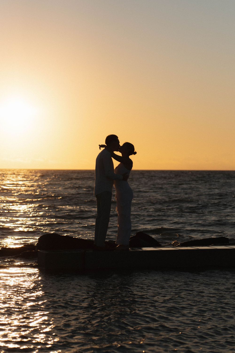 Sunset silhouette of an engaged couple on Honeymoon Island, Florida overlooking the Gulf.