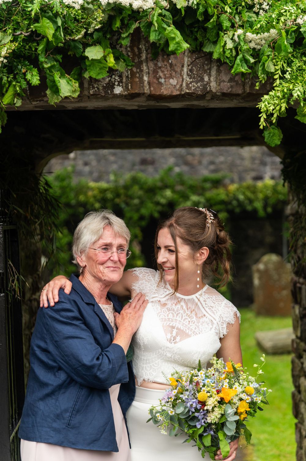 Joyful wedding moments captured under a leafy garden arbor with bright yellow and white floral arrangements.