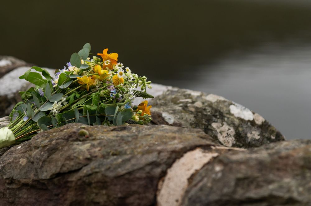 Floral bouquet rests on weathered stone wall with natural light.