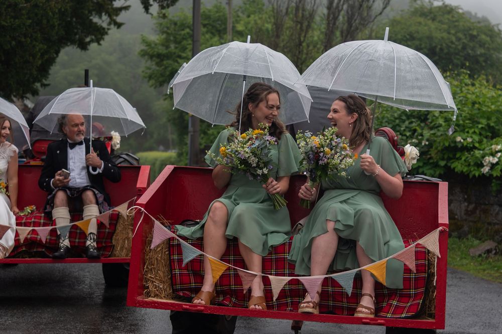 Wedding party shelters under clear umbrellas on rainy celebration day.