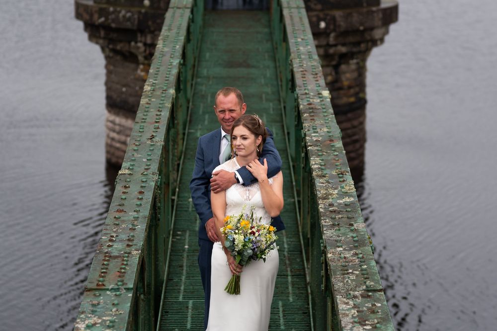 Stone pier walkway extends over calm water with gothic architecture.