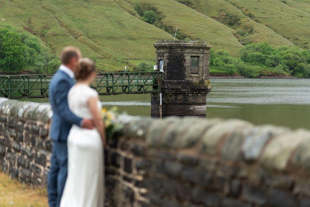 Stone wall spans across green rolling hills beside waterfront.