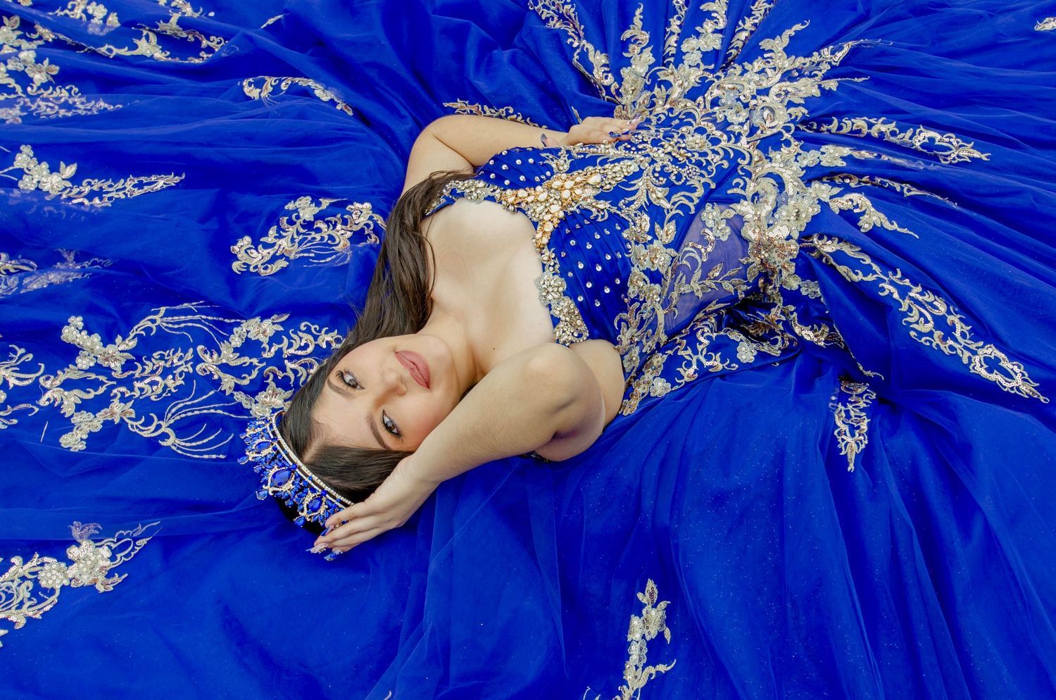 A royal blue ball gown with silver sparkly details is photographed in various poses against a dark background.