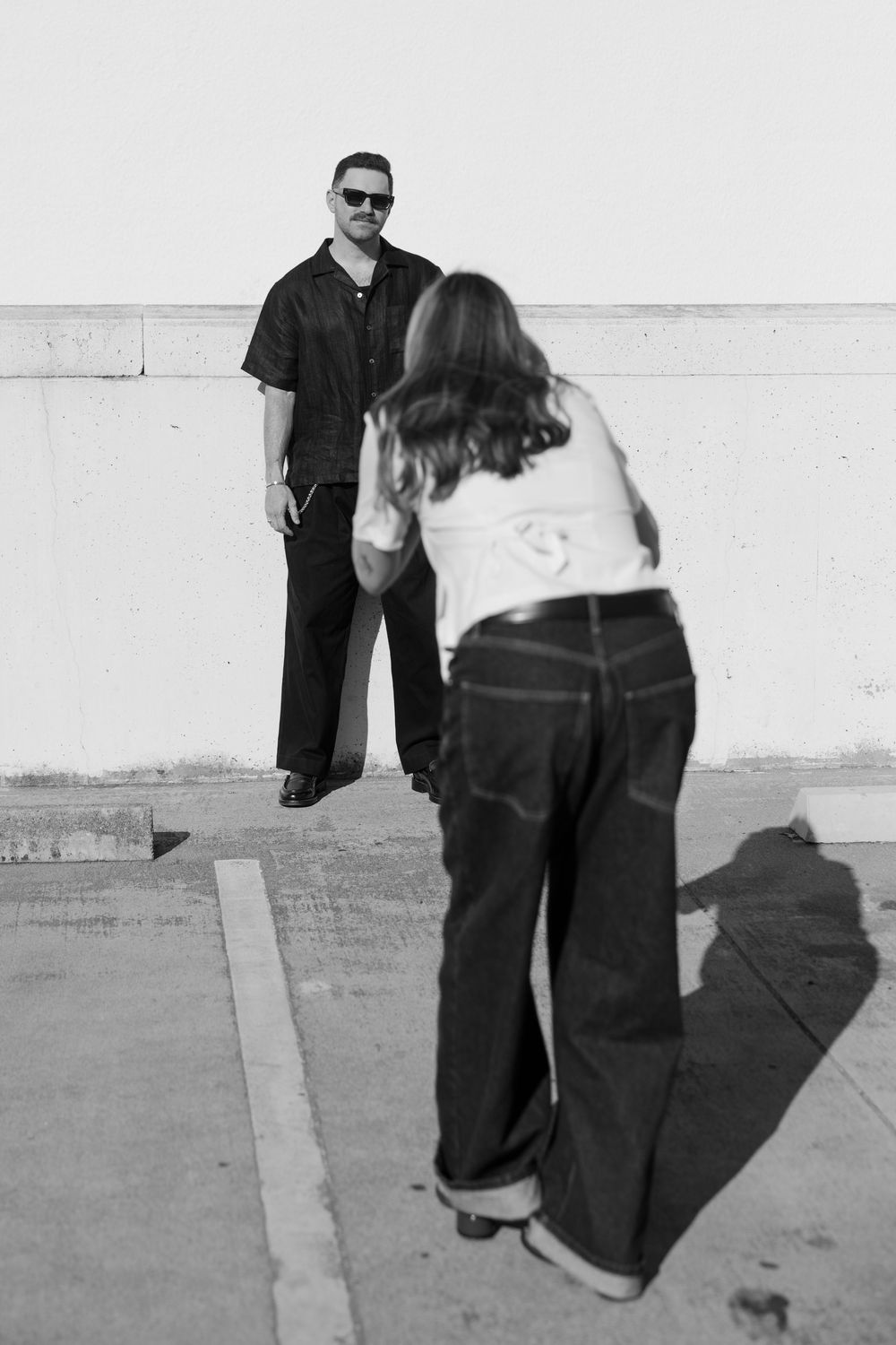 Artistic black and white shot of two people on a sunny rooftop.