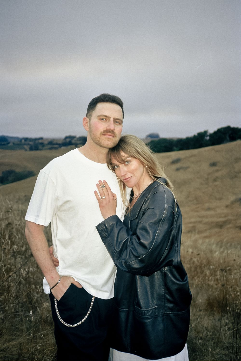 Romantic couple's portrait session in a field wearing contrasting black and white outfits.