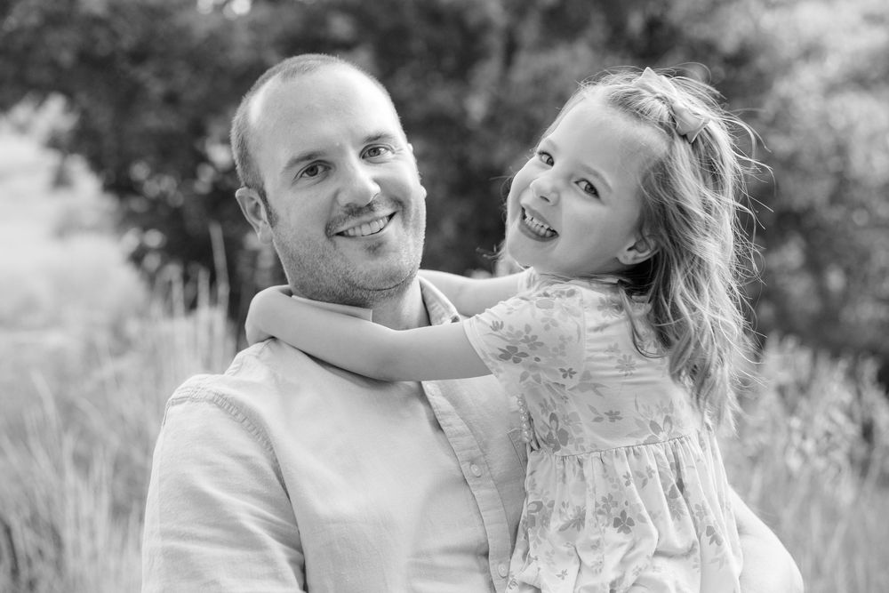 A loving black and white portrait of a parent and child sharing a tender moment outdoors in a natural setting.