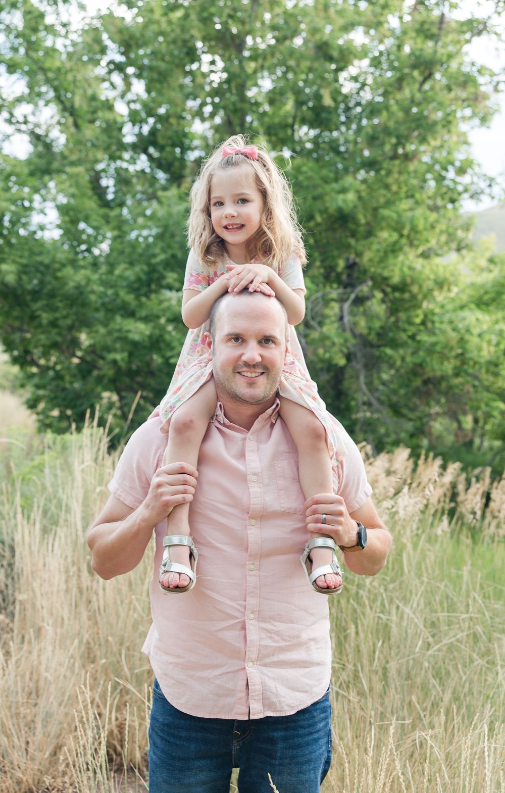 A joyful moment captured outdoors in a grassy field with green trees in the background.