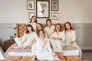 Group wearing matching white robes sits together on a large bed with framed artwork on the wall.
