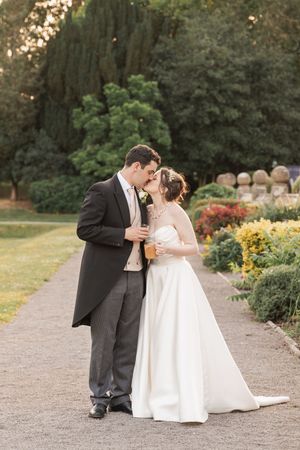 Romantic wedding portraits on a garden path surrounded by colorful summer flowers and greenery.