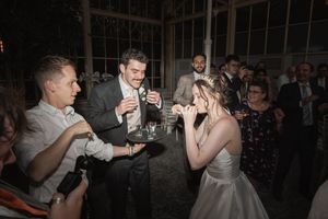 A couple in formal attire dances together at their wedding reception while guests look on and take photos.
