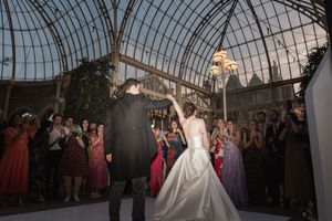 Wedding couple shares their first dance under an ornate glass-domed ceiling at an elegant indoor venue.