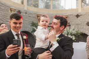 A group celebrates at an elegant indoor venue with drinks while looking at a mobile phone.