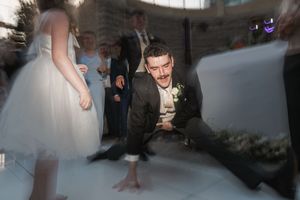 Wedding guest crouches down to dance on a light-up floor at a reception party.
