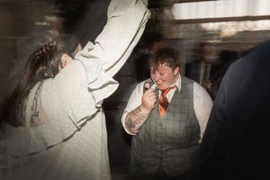 Two figures captured in a dimly lit setting with motion blur, one wearing a gray vest and one in white clothing.