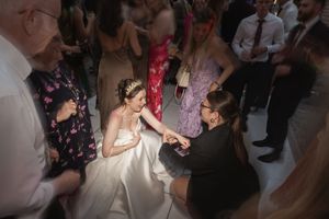 A celebratory dance moment captured at a wedding reception with guests gathered around on the dance floor.