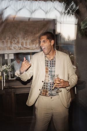 A person in a beige suit dances expressively in a dimly lit indoor space through a series of movement photos.