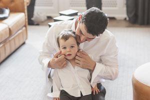 Baby and parent share affectionate moment in casual home setting wearing white clothes.