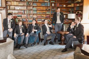 Wedding guests sit together in a library room with bookshelves and wooden furniture.