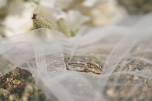 Wedding rings and diamonds sparkle in beautiful macro photography detail against a soft white tulle background.