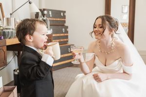A wedding party shares a joyful moment while sipping champagne at an elegant indoor venue.