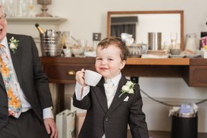 A young boy in formal attire laughs during wedding festivities.