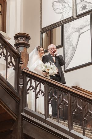 A grand wooden staircase with ornate Gothic details in an elegant interior setting.