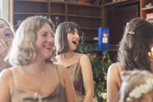 Guests share joyful laughter during a wedding celebration in an indoor venue.