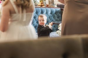 A young guest relaxes on a tufted blue couch during a wedding reception.