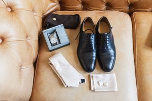 Elegant mens dress shoes in various brown and black leather styles displayed on tufted beige fabric.