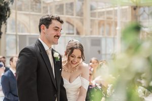 A couple shares a joyful moment during their wedding ceremony in a sunlit courtyard.