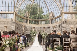 Garden wedding reception setup in a historic greenhouse with chiavari chairs and floral arrangements.