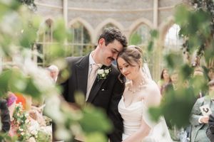 Newlyweds share an intimate moment among green foliage at their wedding venue.