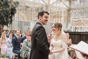 Couple exchanges vows during intimate indoor greenhouse wedding ceremony.