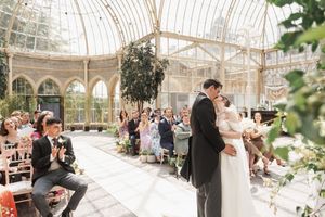 Wedding ceremony in a stunning glass conservatory filled with natural light and greenery.