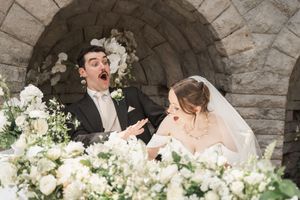 Romantic stone archway decorated with lush white floral arrangements for a wedding ceremony.