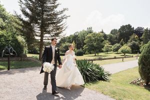 Romantic wedding photo shoot in a lush garden setting with evergreen trees in the background.