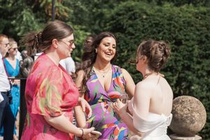Wedding guests laughing and enjoying themselves in an outdoor garden reception setting.