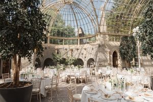 Elegant conservatory wedding venue with glass dome ceiling and tables set for reception.