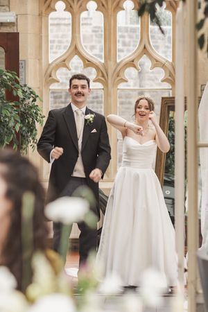 Wedding couple celebrates under ornate Gothic arches in historic venue.