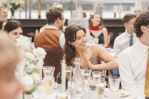 Wedding reception guests enjoy dinner at elegantly decorated tables.