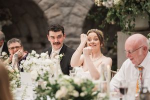 Wedding reception guests celebrate during dinner in romantic candlelit setting.
