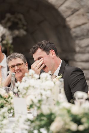 Elegant wedding reception with white floral centerpieces under stone archways.