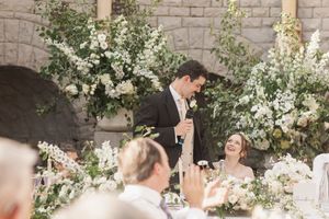 Elegant wedding reception setup with white floral arrangements and stone architectural details.