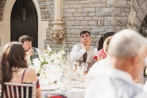 Animated guest reacts during outdoor wedding reception dinner conversation.