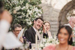 Joyful laughter during an outdoor wedding reception with white floral decorations.