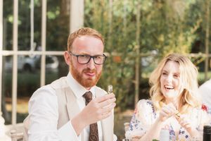 Wedding guests laugh together during a joyful reception moment outdoors.