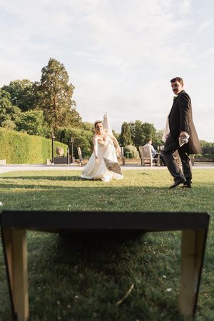 Wedding couple poses on expansive lawn with trees and hedges in background at sunset.