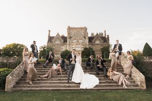 Wedding party members posed on grand stone steps of a historic building.