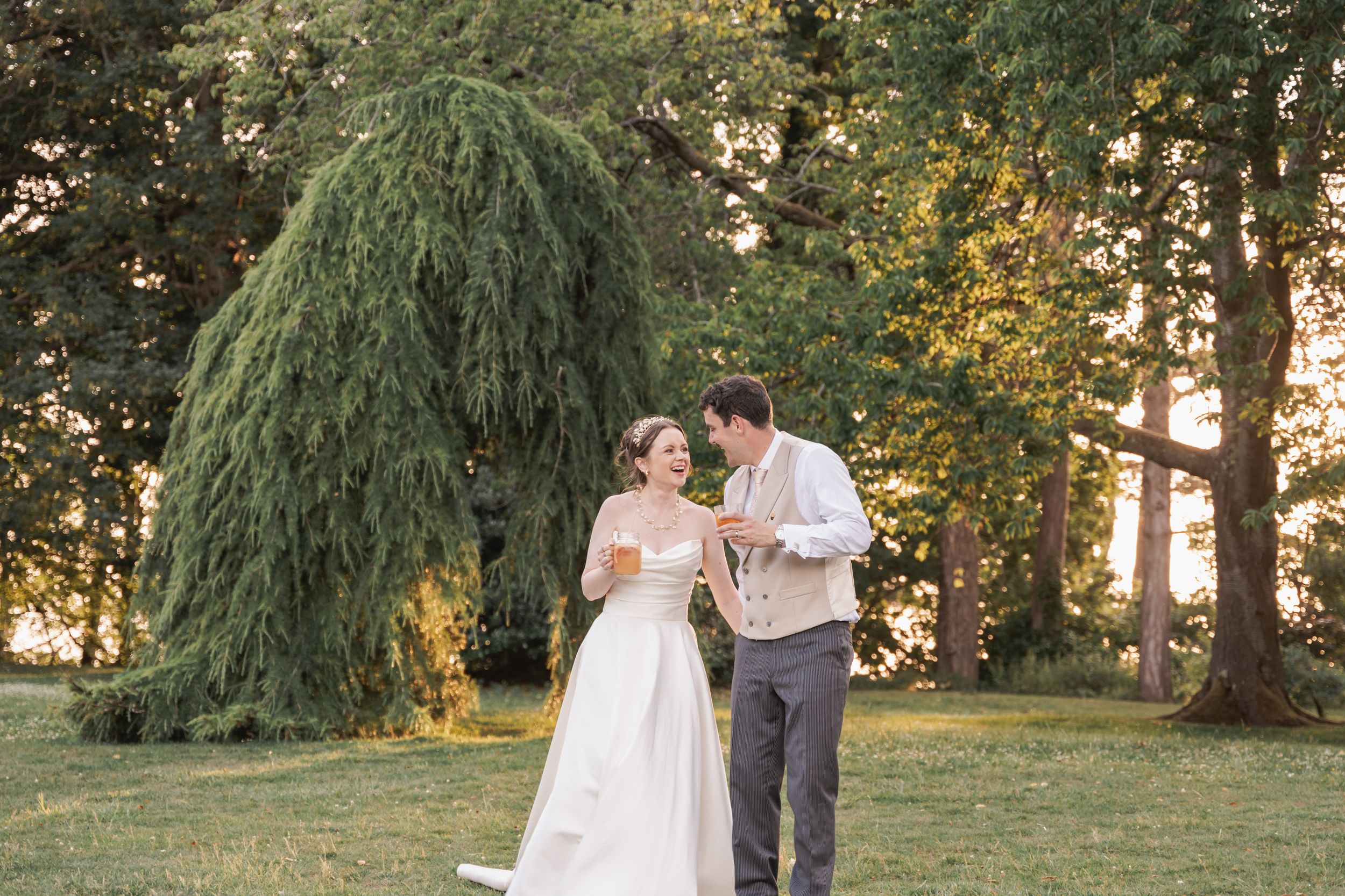 Romantic garden wedding portraits among towering evergreen trees at sunset.