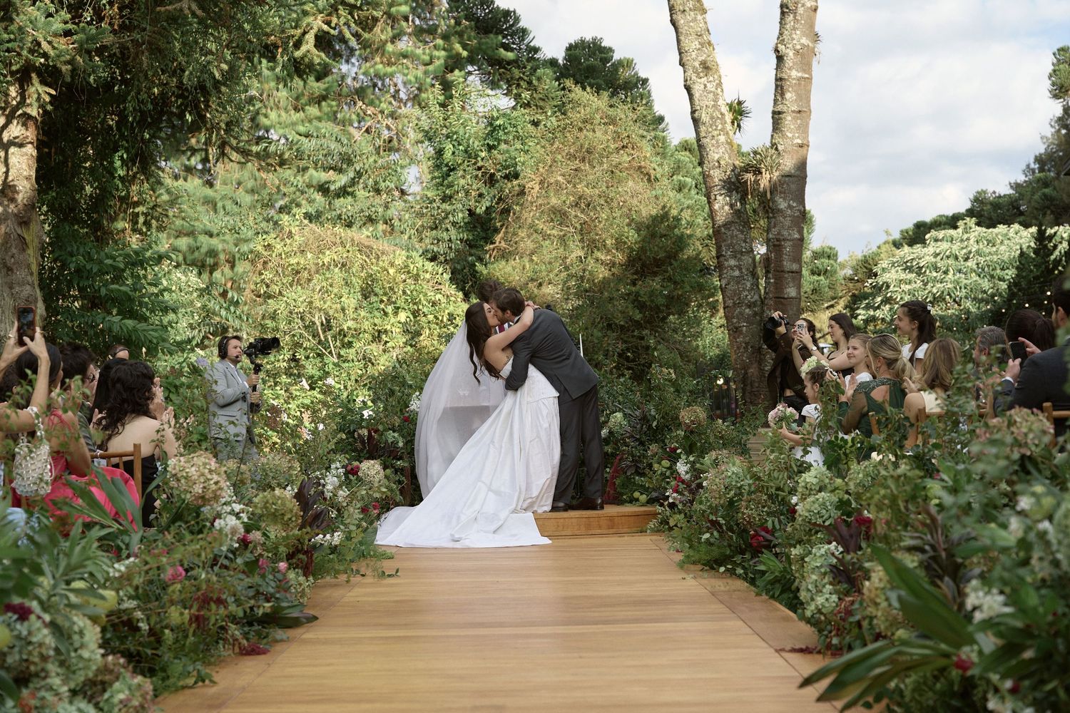 A group of wedding guests dancing and celebrating together on an outdoor patio during a reception party.